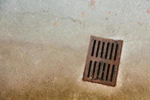 Old rusty metal drainage grid in concrete photo