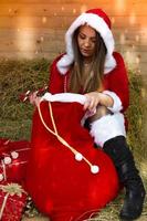 Beautiful girl in Santa costume sits on straw