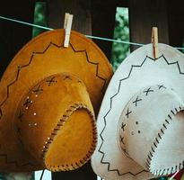 Two decorative leather hats hanging on a line photo