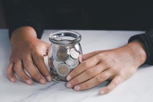 mano sosteniendo un frasco con monedero. concepto de ahorro de dinero. tono oscuro foto