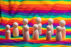 Wooden figure of a person on a rainbow cloth background. lgbtq support group concept. photo