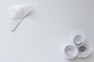 fondo de papel de origami blanco con mariposa y rosas. composición de origami con lugar para tu diseño. arte de papel foto