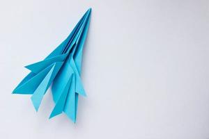 avión de origami de papel azul sobre un fondo blanco. fondo con lugar para texto foto