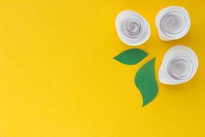 Banner with origami white rose and paper leaves with place for your designon yellow background. Paper background photo