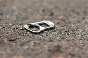 Discarded pull tab from a can lying on the ground photo