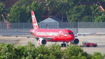 phuket, tailândia, 2 de dezembro de 2018 - airasia a320 9m aqf in we are all champions libré especial sendo empurrada para trás por um caminhão rebocador para a partida do aeroporto internacional de phuket. video