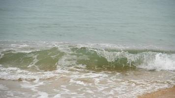 vågor på en sandstrand. may khao beach i norra delen av phuket, slow motion video