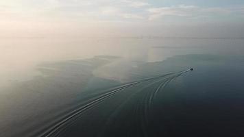 um barco se move nas proximidades de jelutong com ponte de penang como pano de fundo. video