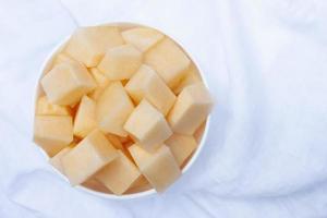 Top View of Sliced Cantaloupe in white bowl on white tablecloth background. photo