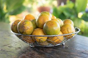 mandarina en una canasta de metal plateado en la vieja madera foto