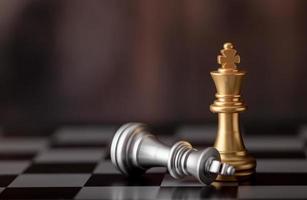 rey de oro de pie y plata cayendo en el tablero de ajedrez foto