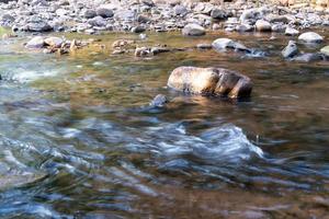 The sunlight hit the rocks in the stream with cool clear water flowing photo