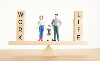 equilibrio entre la vida y el concepto de trabajo. figuras familiares y bloques de madera con palabra en balancín foto