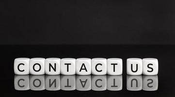 Contact us phrase on white blocks shape on black background. Copy space photo