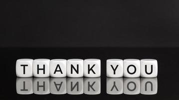 Thank you phrase on white blocks on black background. Copy space photo