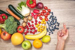 Hand holding food supplements over vegetables and fruits for a healty lifestyle photo