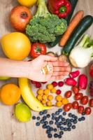 mano sujetando suplementos alimenticios sobre verduras y frutas para un estilo de vida saludable foto