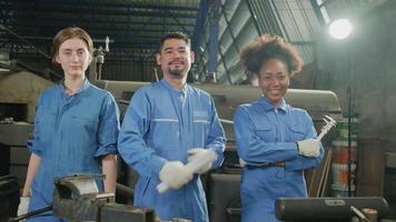 los trabajadores de la industria multirracial con uniformes de seguridad colaboran con unidad, se cruzan de brazos y expresan un trabajo feliz junto con una sonrisa y alegría en la fábrica mecánica, ocupación de ingeniero profesional. video