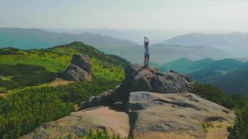 mujer turista se encuentra sobre una roca con los brazos levantados, a una altitud de 1700m. hermoso paisaje de los cárpatos ucranianos. amanecer en las montañas mañana en las montañas