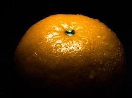 Water droplet on glossy surface of freshness orange on black background photo