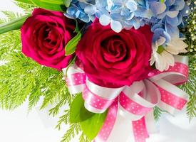 Big red roses and small blue fragile flowers insert leaves in the beautiful flower bouquet photo