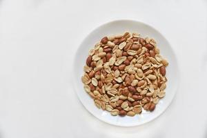 Fried delicious peanuts on a white plate close-up photo