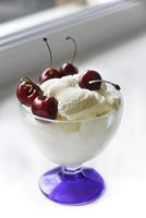Creamy sweet ice cream in a glass ice cream maker with large cherry berries photo
