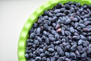 Fruits of honeysuckle berries in a basin on a white background photo