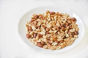 Fried delicious peanuts on a white plate close-up photo