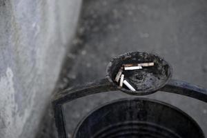 un bote de basura en la calle con un lugar para cigarrillos foto