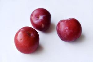 Juicy fresh red plums on a white background photo