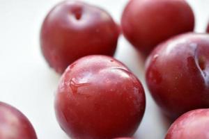 Juicy fresh red plums on a white background photo