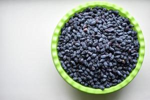 Fruits of honeysuckle berries in a basin on a white background photo