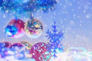 Close up christmas balls and snowflake hanging on the branch of the pine with snow falling photo