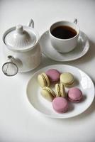 tetera de porcelana con una taza de té y pasta sobre un fondo blanco. foto