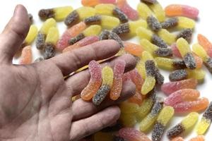 Sugar delicious marmalade worms in your hand on a white background photo