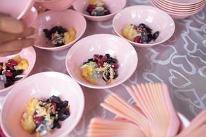 Preparing bowls of ice kacang or bean ice which is placed on a table. It is a popular dessert in Malaysia and Singapore photo