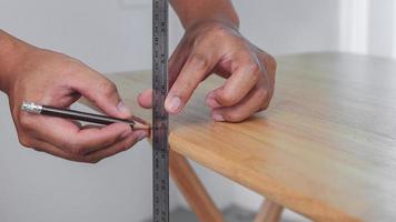 concepto de medición. alguien mide una artesanía de mesa por regla. Fácil trabajo de bricolaje o artesanía. foto