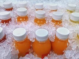 Bottles of fresh fruit juices in the ice bucket, which are orange juice, passion fruit juice, pineapple juice photo