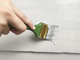 Hand holding brush painting wall photo