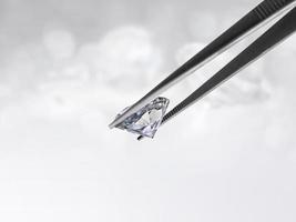 Dazzling diamond held in tweezers on a bokeh background photo