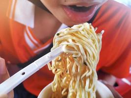 niña asiática comiendo fideos instantáneos foto