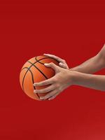 manos y baloncesto aislado sobre fondo rojo. foto