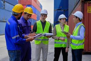 A Group of multiracial workers people in safety uniforms and hard hats work at logistics terminal with many stacks of containers, loading control shipping goods for the cargo transportation industry. photo