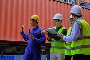A Group of multiracial workers people in safety uniforms and hard hats work at logistics terminal with many stacks of containers, loading control shipping goods for the cargo transportation industry. photo