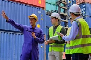 A Group of multiracial workers people in safety uniforms and hard hats work at logistics terminal with many stacks of containers, loading control shipping goods for the cargo transportation industry. photo