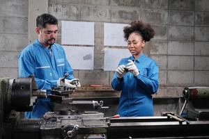 Two professional industry workers in safety uniforms and engineers' partner worked with precision metalwork tools and discussed mechanical drawing for lathe machines workshop in manufacturing factory. photo