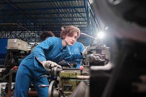 Professional young White female industry engineer worker works in safety uniform with metalwork precision tools, mechanical lathe machines, and spare parts workshop in the steel manufacturing factory. photo