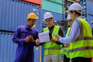 A Group of multiracial workers people in safety uniforms and hard hats work at logistics terminal with many stacks of containers, loading control shipping goods for the cargo transportation industry. photo