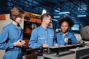 Multiracial professional industry engineer teams in safety uniforms work by inspecting machines' voltage current, checking, and maintaining at manufacture factory, electric system service occupations. photo